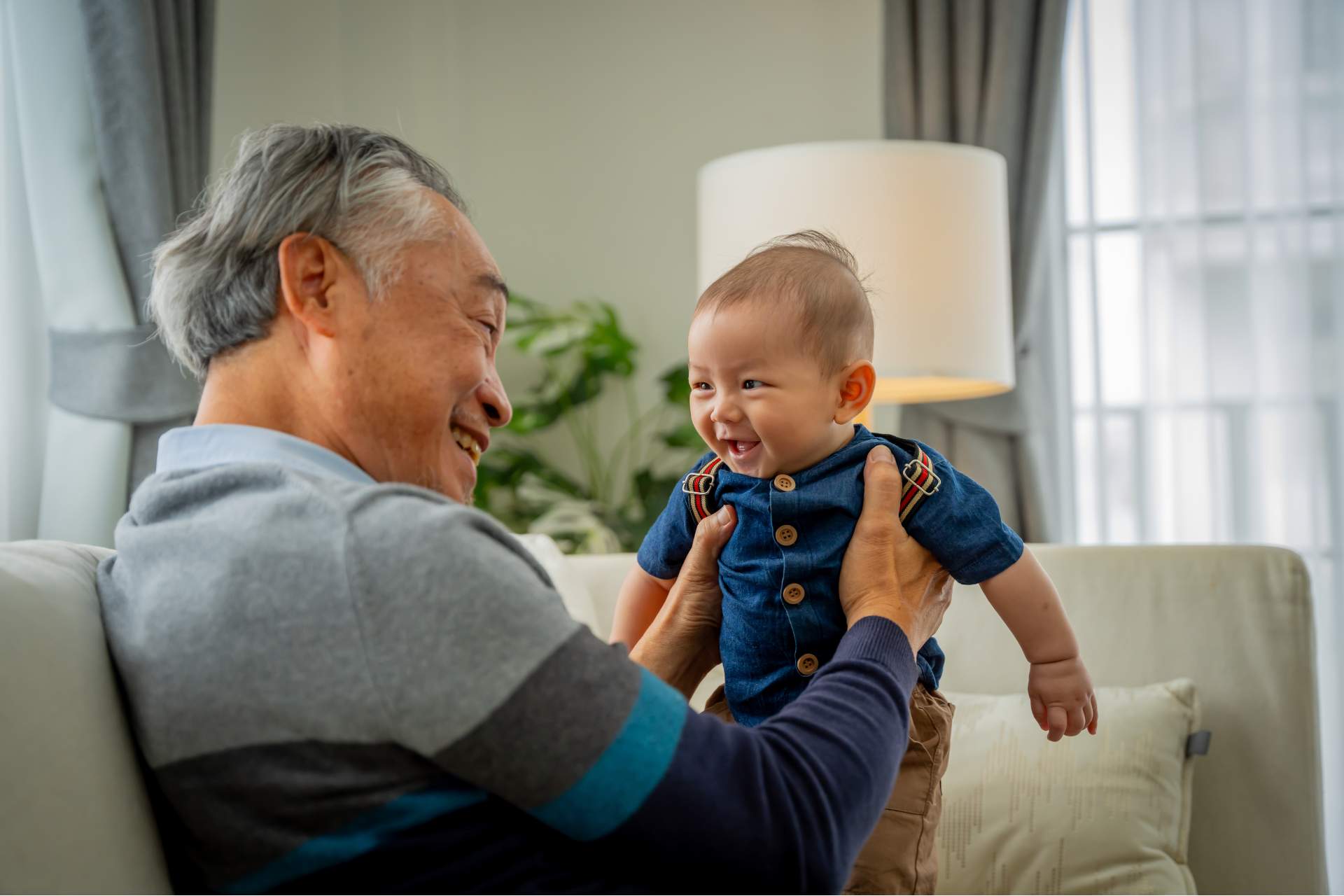 A smiling senior man holding a smiling baby